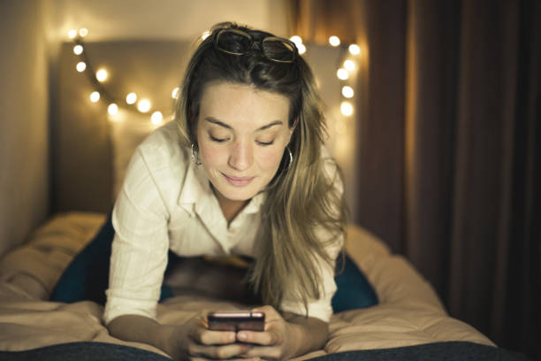 istock Pretty Caucasian female using her cellphone while sitting on her bed 1459921686