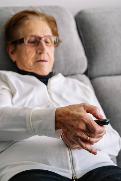 istock Old grandma changing the channel while watching TV 1459922051
