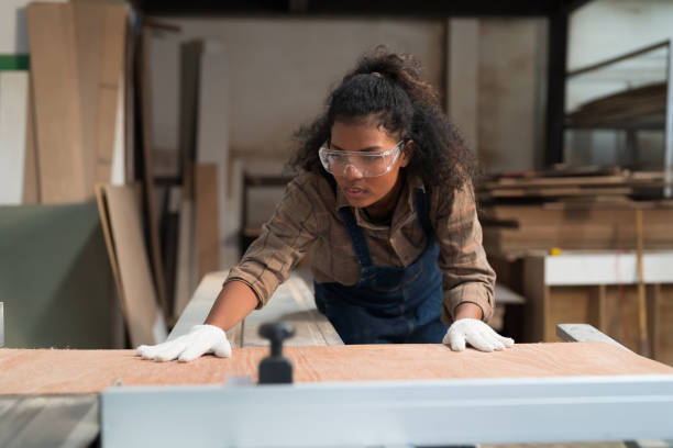 istock African American female carpenter worker working with saw machine at wood processing plant. Female joiner worker in safety uniform and equipment tools working in wood factory. Manufacturer industry m 1459923069