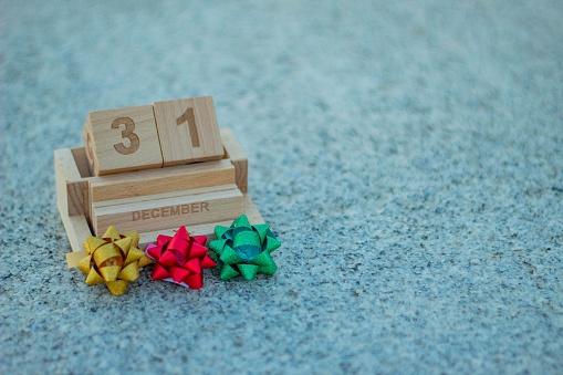 Wooden calendar with the date of the last day of the year, December 31, New Year's Eve with small colored bows of Christmas gifts.
