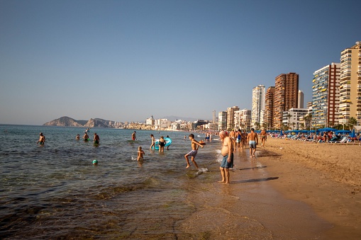 Benidorm, Spain – November 01, 2022: Tourists bathing on the beach of Benidorm in Alicante on a sunny November day with an enviable climate and calm Mediterranean sea.