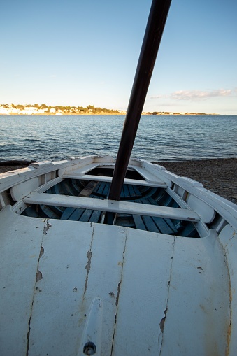 Barco blanco aparcado sobre las piedras de una de las playas de la localidad de Cadaqués al lado. photo