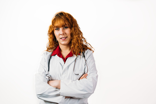 Portrait of caucasian beautiful young woman doctor or intern wear red uniform isolated, studio shoot. Medical person
