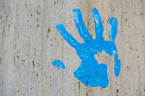 A close up shot of blue handprint on the gray wall