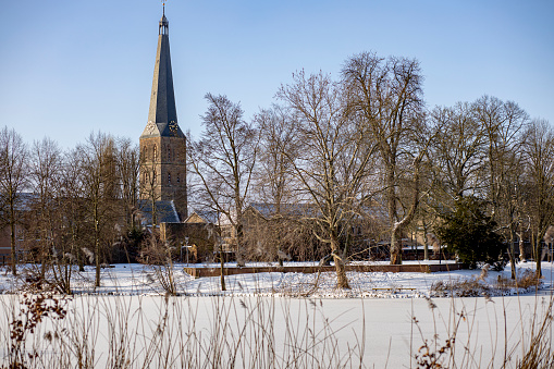 Picturesque painterly landscape of thick pack of snow on vegetation with the Nieuwestadskerk church and tower in Zutphen, The Netherlands,