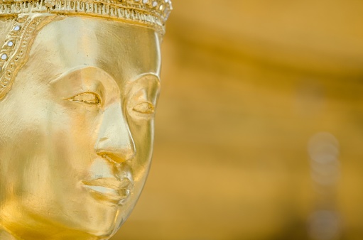 A soft focus of the head of a golden serene Buddha staute