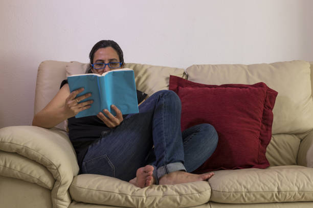 istock Caucasian girl enjoying a book on a sofa 1459928709