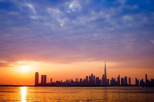 A scenic sunset above a tranquil beach with the Dubai skyline in the background on a summer day