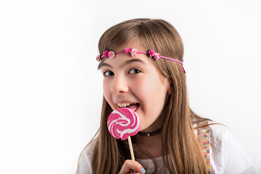 A Spanish little girl eating a lollipop on a white background