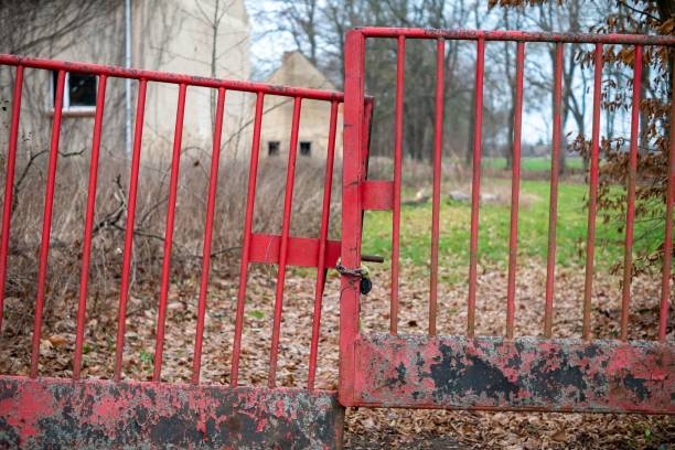 istock Closed and chained broken red gate in a farm 1459929476