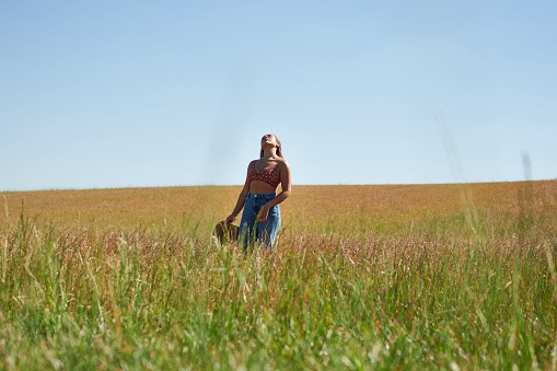 A beautiful Hispanic young woman in a field under a blue sky.