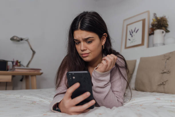 istock Anxious Caucasian female looking at the phone while lying on her bed 1459929934