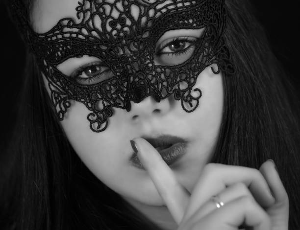 A Hispanic young woman with a carnival mask-making silent gesture in grayscale