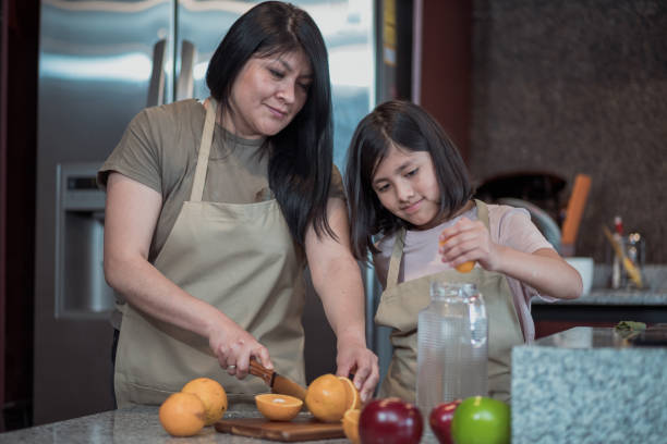 istock Mexican mother and daughter making orange juice in the kitchen 1459930721
