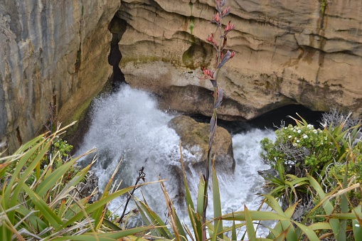 Splashy flowing water surrounded by rocky cliffs in Pancake Rocks, New Zealand