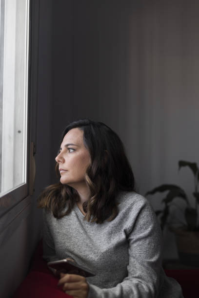 istock woman looking out the window 1459933340