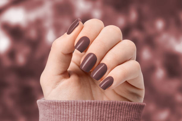 su uno sfondo di foglie marroni, le mani di una donna hanno una manicure alla moda. - nail salon fingernail manicure design foto e immagini stock