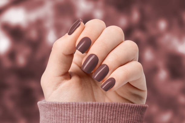 istock On a brown leaf background, a woman's hands have a trendy manicure. 1459934091