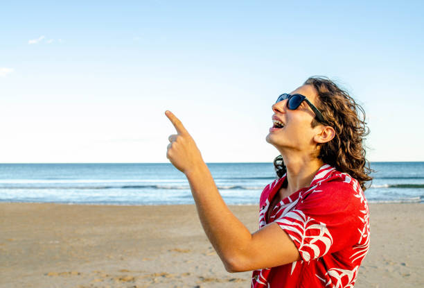 young handsome long hair man with sunglasses and red hawaiian shirt pointing up with his finger with - shaved head imagens e fotografias de stock