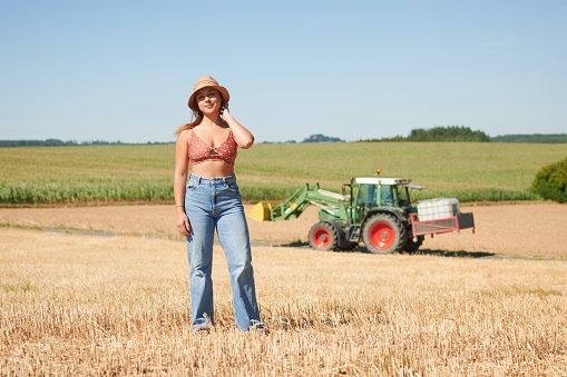 A portrait of a Hispanic woman wearing a hat posing in a wheat field on a sunny day