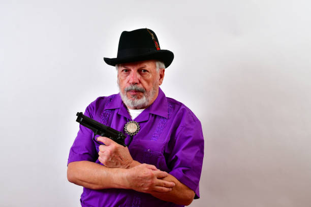 serious senior man holding a 9mm automatic pistol is making an offer that can't be refused - 偷拍的照片 個照片及圖片檔