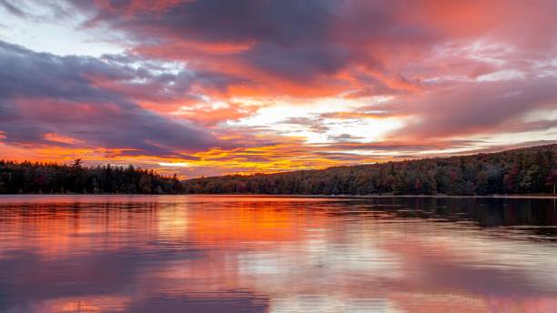 istock Beautiful sunset sky with dense clouds and orange hues reflecting on a lake surrounded by trees 1459934747