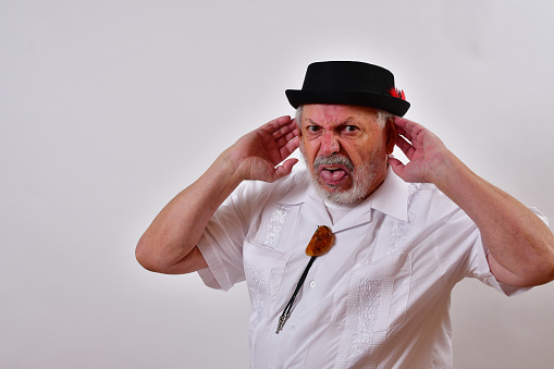 A view of an elderly man gesturing that he cannot hear on a white background