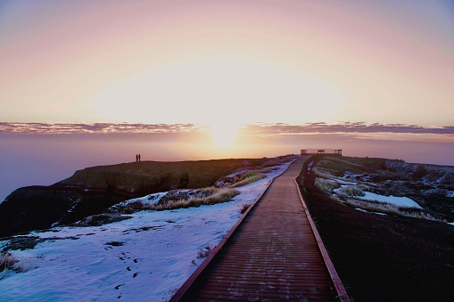 A trail in mountains covered with snow in Badlands National Park, South Dakota at sunset