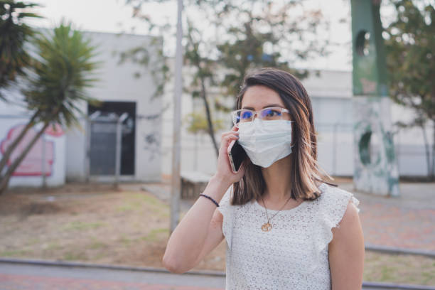 istock Woman in a mask making a call with her cell phone 1459936881