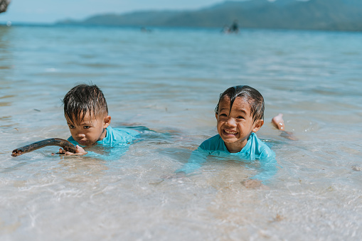 Happy Twins Kids have Fun on White Sand Beach. Filipino Asian Children Playing at Sea on family summer vacation on an exotic island in the Philippines