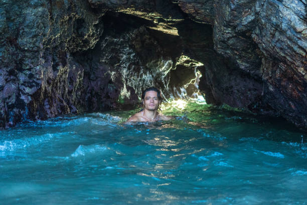 istock Attractive young male relaxing along inside a cave in the water 1459939910