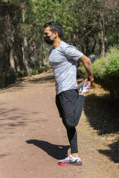 istock young latin man doing leg stretching exercises before running in the morning. 1459940121