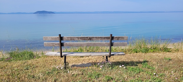 A panoramic view of an old wooden bench on the background of the sea