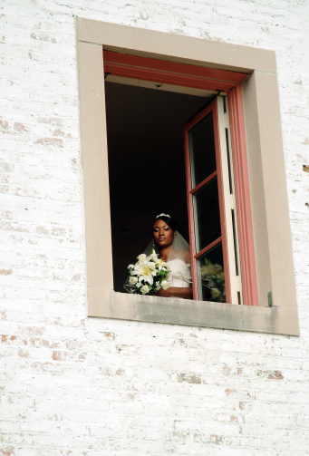 African American bride looking through window