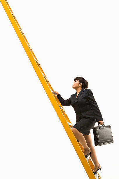 Businesswoman climbing ladder of success stock photo