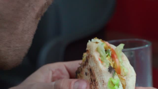 Young man eating a sexy juicy beef hamburger in close-up