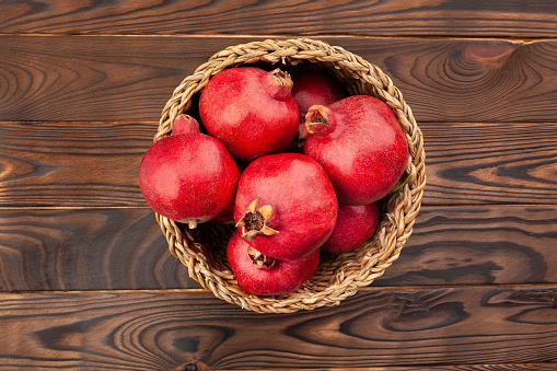 pomegranate in a basket on wood background top view