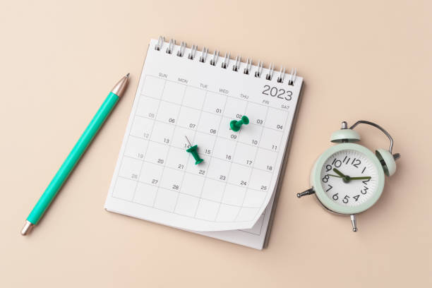 istock Calendar with pen and clock on pastel beige background 1459945116