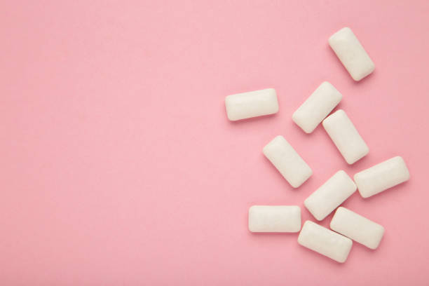 istock Chewing gum pieces on pink background. Space for text 1459946207
