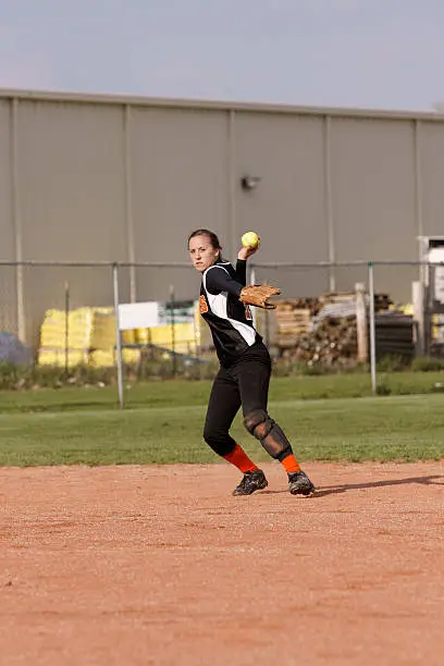 shortstop ready to throw to first in a girls softball game
