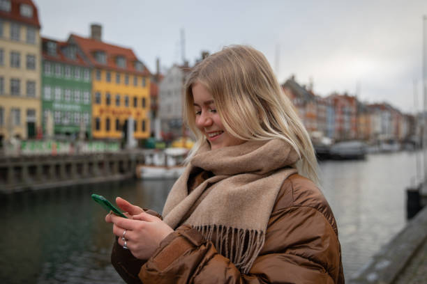 ein zufriedenes mädchen benutzt ihr smartphone, während es in der innenstadt von kopenhagen ist. - tourism travel europe northern europe stock-fotos und bilder