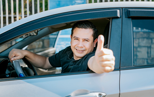 Happy Driver giving a thumbs up. Satisfied driver man showing thumb up. Concept of satisfied car owner, Man in his car giving thumbs up