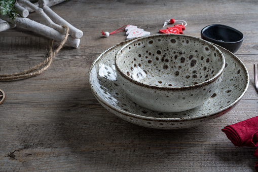 Christmas themed table setting with ceramic bowl, ornamental decorations on a rustic timber surface.