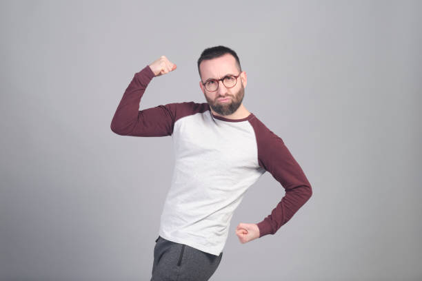 Young man flexing his arms in funny way in a studio shot