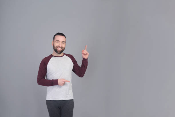 istock Young man standing pointing at copy space in a studio shot 1459951216
