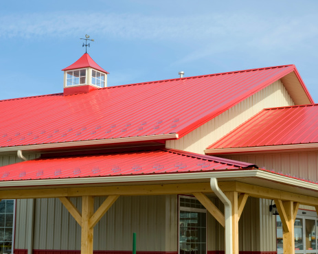 Red metal roofed building with weather vain.