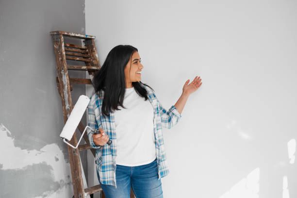 istock Young woman gestures to painted wall showing home DIY progress before and after 1459953443