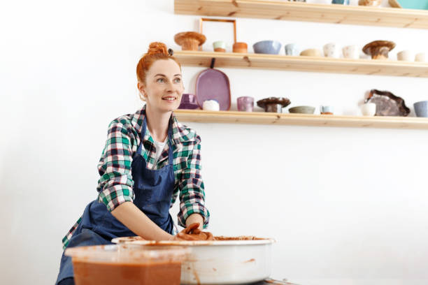 istock Happy female sculptor making clay pot on pottery wheel 1459954538