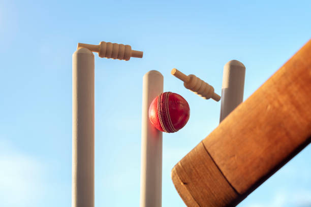 Cricket ball hitting wicket stumps knocking bails out stock photo