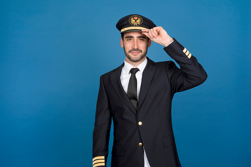 Studio portrait of an airline pilot Airline pilot greeting with his hat greeting with his hat